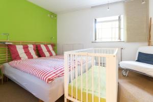 魏玛阿尔特法尔内雷公寓的一间卧室设有一张婴儿床和一面绿色的墙壁