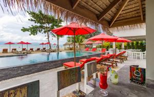 班泰la plage resort & beach club的一个带红色遮阳伞和桌椅的游泳池