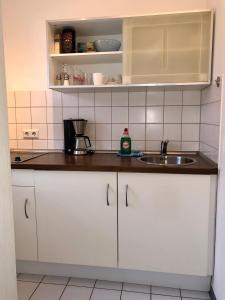 吉森Bed & Kitchen的厨房配有白色橱柜和水槽