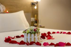 舍诺夫The Originals City, Hôtel Armony, Dijon Sud (Inter-Hotel)的花瓶,床上有红玫瑰花瓣