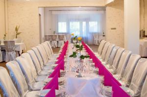 可罗日采Resort Jura的一张长桌子,配有白色椅子和粉红色的桌边跑步机