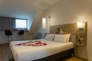 舍诺夫The Originals City, Hôtel Armony, Dijon Sud (Inter-Hotel)的酒店客房,配有一张红色鲜花的大床