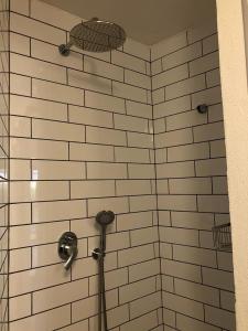 埃拉特A secret Oasis的配有白色瓷砖墙壁和淋浴头的淋浴