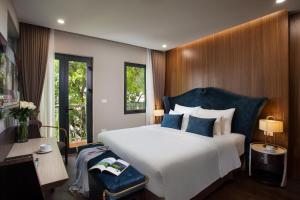 河内Hanoi L'Heritage Diamond Hotel & Spa的卧室配有带蓝色枕头的大型白色床