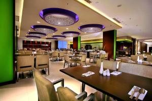 普禾加多ASTON Purwokerto Hotel & Conference Center的餐厅设有桌椅和紫色灯