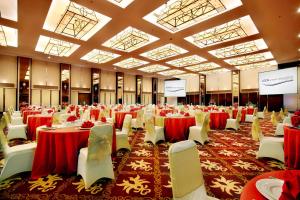 普禾加多ASTON Purwokerto Hotel & Conference Center的一个带红色桌子和白色椅子的大型宴会厅