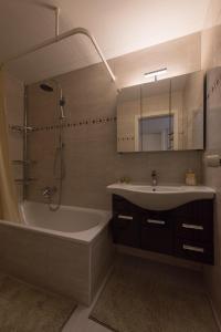 阿劳Muhusin Apartments的带浴缸、水槽和镜子的浴室