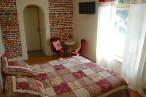Tigny-NoyelleLa Ferme De Tigny的一间卧室设有一张床和砖墙
