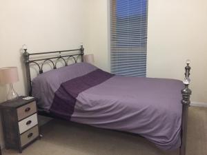 斯特利特Flat 2的一间卧室配有一张带紫色床单的床和床头柜。