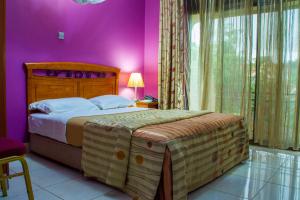 坎帕拉Landmark View Hotel的一间卧室设有一张紫色墙壁的大床