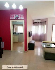 CocodyAppart Sly Abidjan的带沙发和红色墙壁的客厅