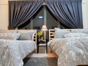 普崇Puchong 8-12 pax 5min LRT Cozy Apartment IOI Mall的卧室内的两张床,配有蓝色窗帘