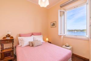 科孚镇Mouragia Luxury Seaview Suite by Konnect的卧室配有粉红色的床和窗户。