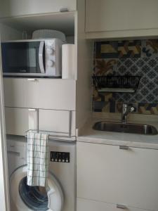 里斯本Casa da Tia Adozinda的厨房配有洗衣机和微波炉。