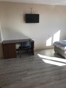 HacıbektaşGunes Hotel的一间卧室配有书桌、一张床和一台电视。