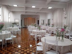 里贝朗普雷托Aurora Hotel的宴会厅配有白色的桌椅和鲜花