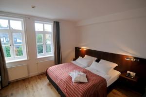 文斯托夫伯格曼斯霍夫酒店的一间卧室配有一张带红色毯子的床和两个窗户。