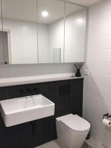 特里格尔Modern & Cozy Unit Just Steps from Terrigal Beach的一间带水槽、卫生间和镜子的浴室