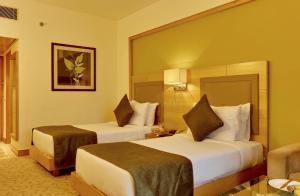 新德里新德里苏尔亚酒店的酒店客房,配有两张床和椅子