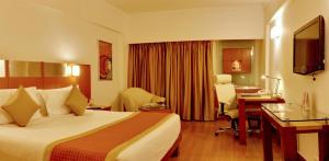 新德里新德里苏尔亚酒店的配有一张床和一张书桌的酒店客房