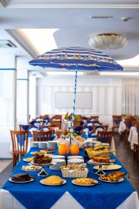 里米尼Hotel Holland的一张长桌,上面放着食物盘子和雨伞