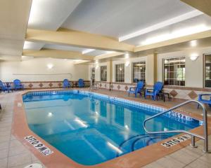 斯普林代尔Sleep Inn & Suites Springdale West的酒店客房的大型游泳池配有蓝色椅子