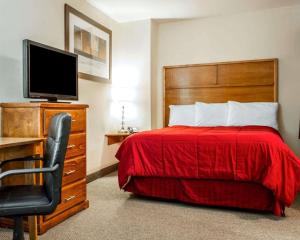 尤里卡Sea Drift Inn的一间卧室配有一张带红色床罩的床和电视。