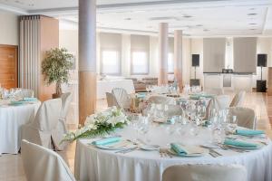 Granda扎尔唐费尔南多酒店的宴会厅配有白色的桌椅和鲜花
