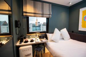 都柏林The Devlin Dublin的酒店客房设有一张床、一张书桌和两个窗户。