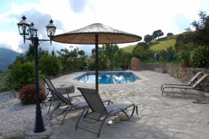 埃尔加斯托尔拉嘉因农家度假屋的一组椅子和一把遮阳伞,位于游泳池旁