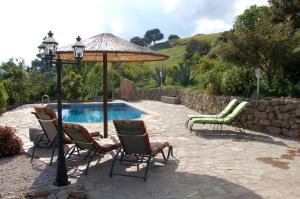 埃尔加斯托尔拉嘉因农家度假屋的一组椅子和一把遮阳伞,位于游泳池旁