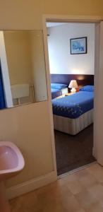 布莱克浦Hotel Avano - Pleasure Beach的浴室设有镜子、一张床和一个水槽