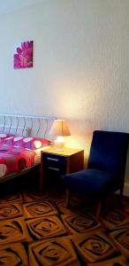 布莱克浦Hotel Avano - Pleasure Beach的一间卧室配有一张床、一把蓝椅和一盏灯