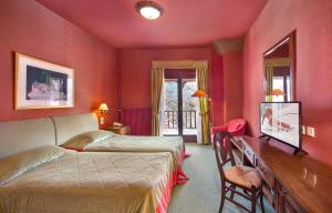 米克隆科利奥Country Club Hotel & Suites的一间卧室设有红色的墙壁、一张床和一张书桌