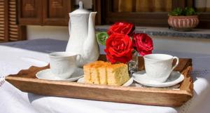 埃拉蒂特里卡隆弗莱特扎托公寓式酒店的盘子,盘子上放着两个杯子,蛋糕和玫瑰