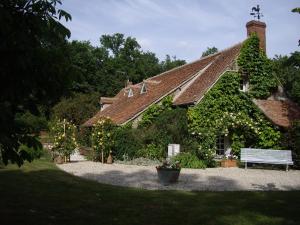 Vitry-aux-LogesLes Sapins的常春藤覆盖的房子,前面有长凳