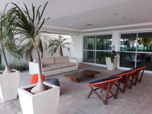 若昂佩索阿Flat Jardins do Atlântico, frente mar的带沙发和棕榈树的客厅