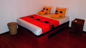 平纳瓦拉Luck Uyana Cabana Pinnawala的一张带橙色枕头和红色毯子的床