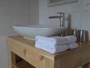La BréoleMaison d'hôtes l'Arnica的浴室设有水槽和木桌上的毛巾