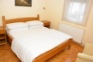斯雷姆斯卡米特罗维察过客住宿加早餐旅馆的一间卧室配有一张带白色床单的大床