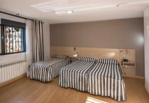 阿维拉神圣之门酒店的一间卧室设有两张床和窗户。