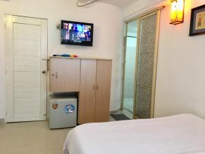 胡志明市Baoanh Hostel的卧室配有一张床,墙上配有电视。