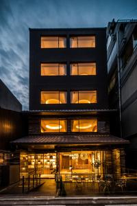 京都Kyoto Shijo Takakura Hotel Grandereverie的前面有桌椅的黑色建筑