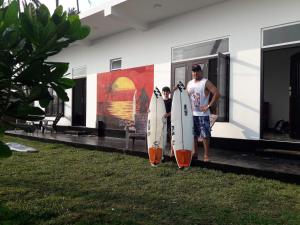 马特勒夕阳冲浪海滩度假村的两人在大楼前拿着冲浪板