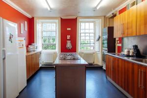 邓迪Dundee Backpackers Hostel的厨房设有红色的墙壁和白色的冰箱