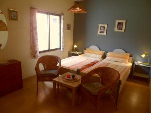 塔扎克蒂天堂度假屋的一间卧室配有一张床、两把椅子和一张桌子
