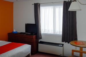 温莎大瀑布Hotel Robin Hood的一间卧室配有一张床、一台电视和一个窗口