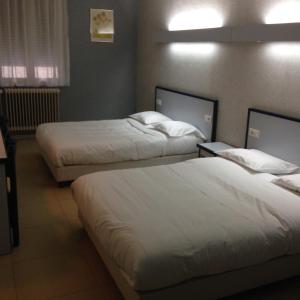 卢昂HOTEL DU JURA的配有白色床单的酒店客房内的两张床
