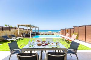 罗希姆诺Espera, Luxury Beach Front Residence, By ThinkVilla的游泳池旁的餐桌上放着食物