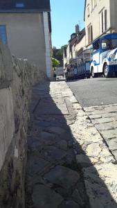 沙特尔Décor Appart'的一条石头人行道,旁边是一条有巴士的街道